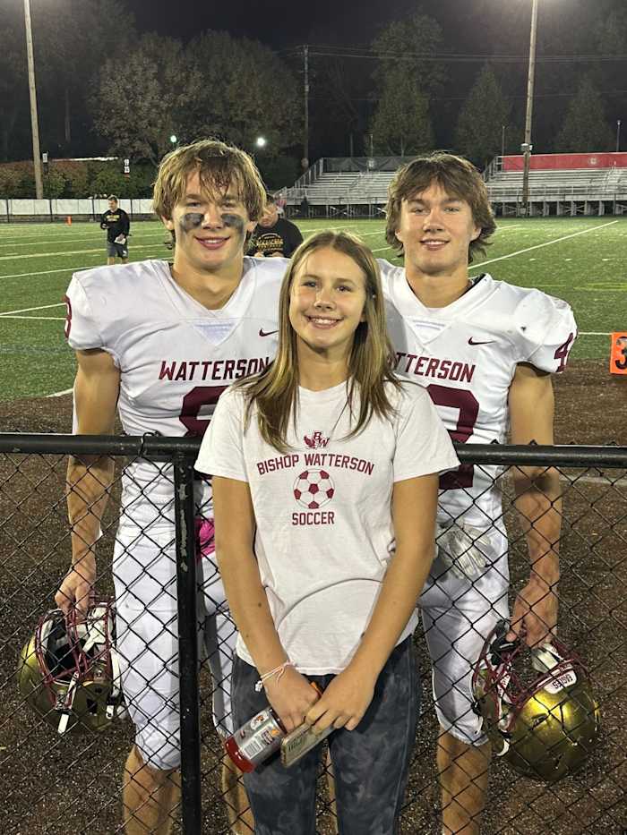 The three Uhlenhake kids - Allie (in front), Jake (No. 8) and Ben (No. 42) pose for a photo after a football game.